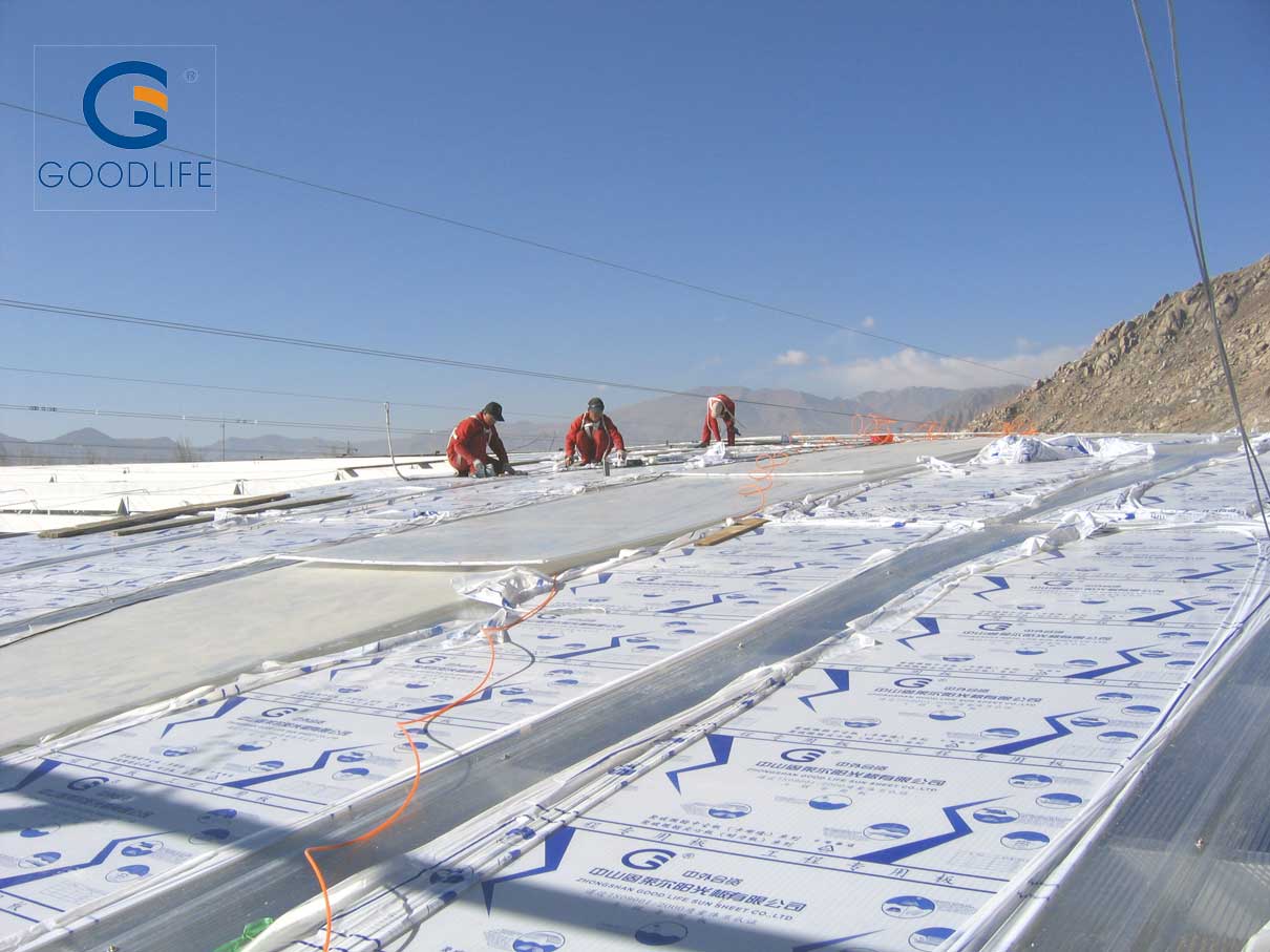 Trabajadores instalando placas de policarbonato Goodlife de 16 mm con película protectora en Lhasa Sun City