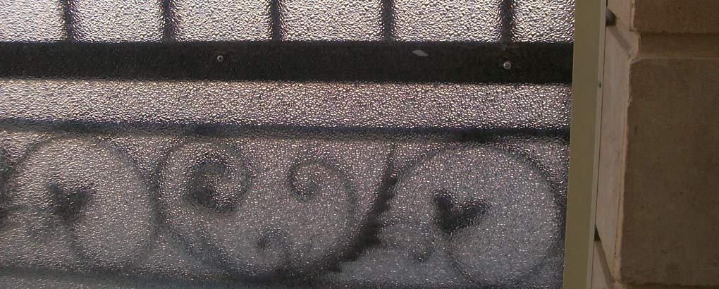 Placa sólida de policarbonato con forma de diamante utilizada en una puerta, permitiendo el paso de luz mientras mantiene la privacidad